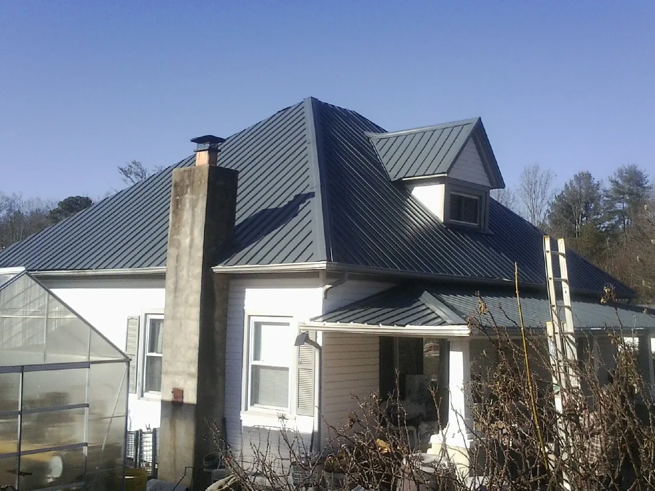 Dark blue standing seam metal roof on a white farmhouse with dormer — Slate & Tile Roof Repair by Roofing Brothers in Cygnet