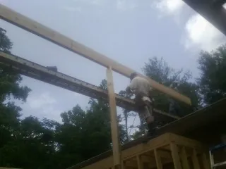 Carpenter setting a ridge beam over a new addition frame — Ice Dam Removal by Roofing Brothers in Cygnet