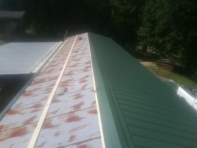 Old rusted panels beside newly installed green metal roofing — Wind Damage Roof Repair by Roofing Brothers in Cygnet