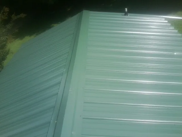 New green metal panels meeting at the ridge of a roof — Flat Roof Repair work by our crew in Cygnet