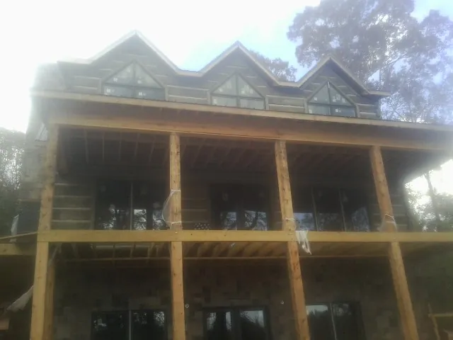 Dormers and porch framing on a large log home under construction — Roof Coating work by our crew in Cygnet