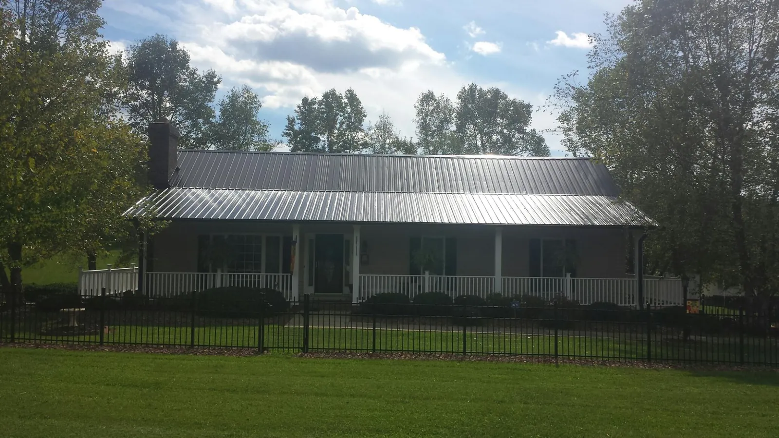 Gray metal roof on a brick ranch with a full width front porch — Gutter Guard Installation work by our crew in Cygnet