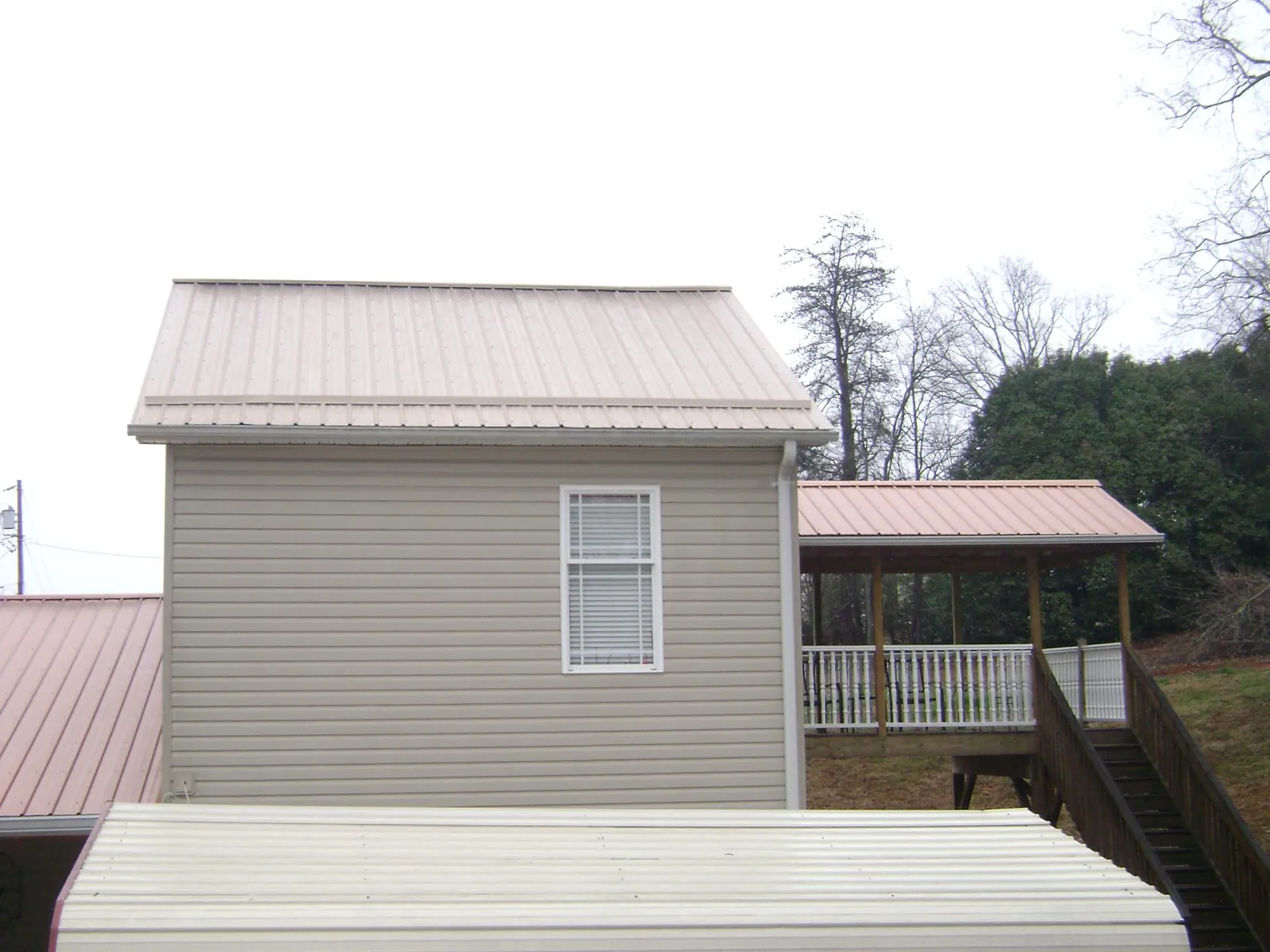 Tan metal roofs on a two story addition and attached porch, from a Roof Replacement job in Cygnet