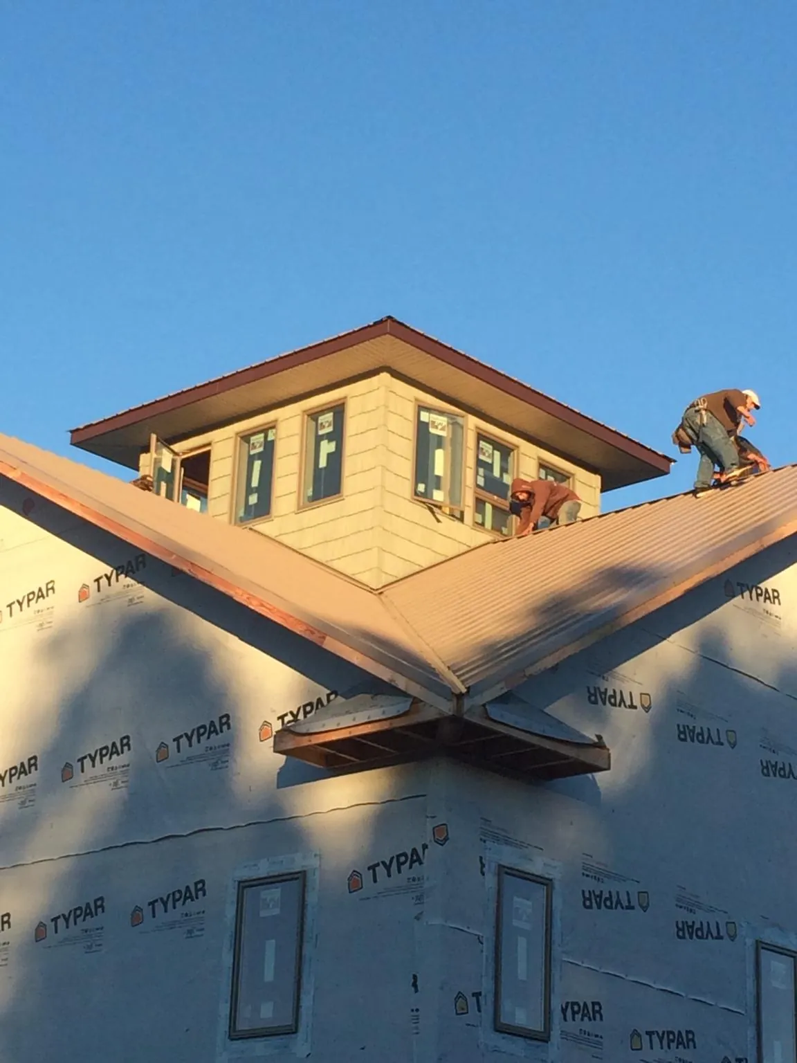 Roofers working around a rooftop cupola on a new metal roof at sunset — Roof Waterproofing in Cygnet by Roofing Brothers